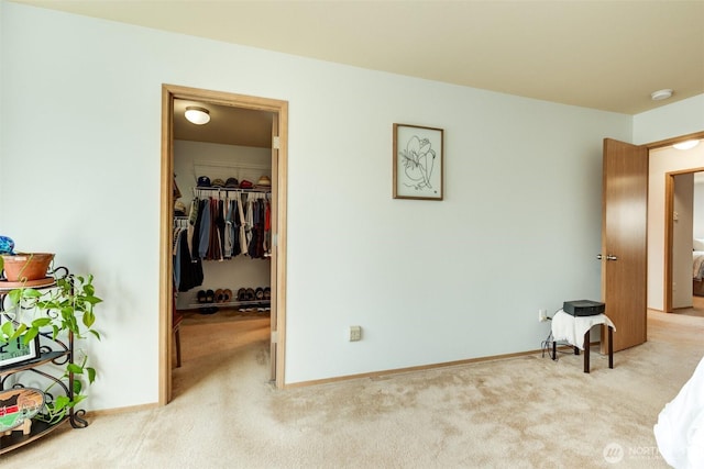 bedroom with a closet, a spacious closet, carpet, and baseboards