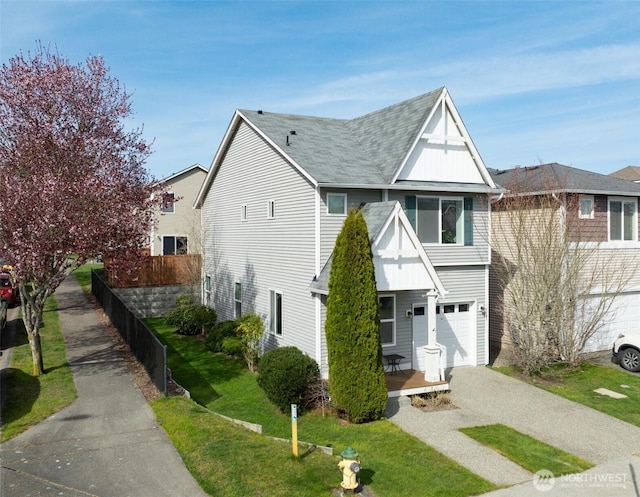 view of front of property featuring roof with shingles, driveway, a front lawn, a garage, and fence
