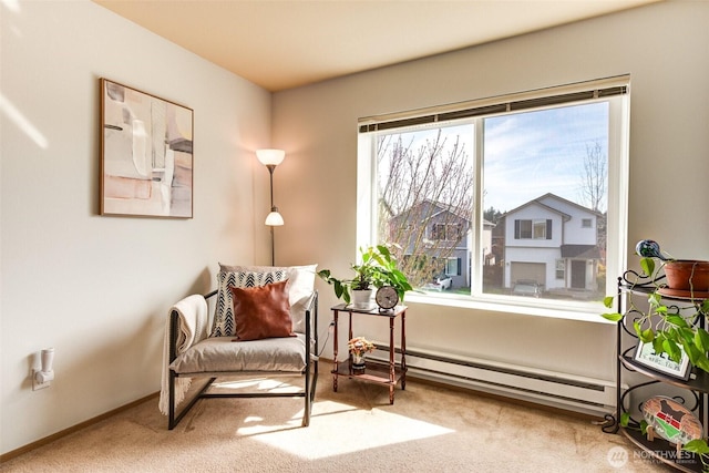 sitting room with a baseboard heating unit, baseboards, and carpet