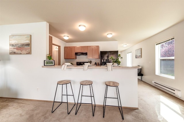 kitchen featuring a peninsula, black appliances, baseboard heating, under cabinet range hood, and a breakfast bar area