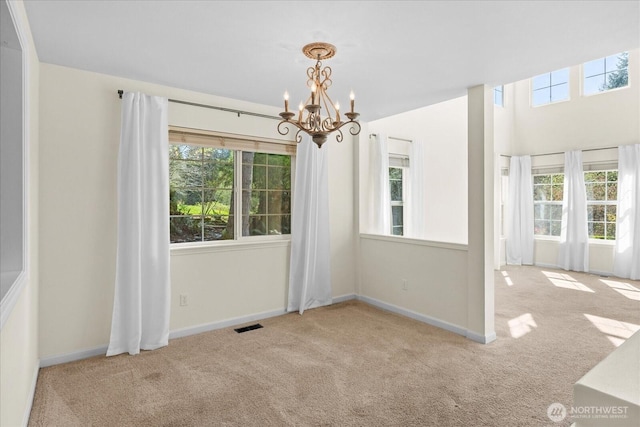 unfurnished dining area with visible vents, an inviting chandelier, baseboards, and carpet