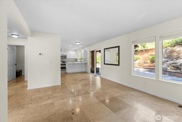 unfurnished living room featuring visible vents, baseboards, and a sink
