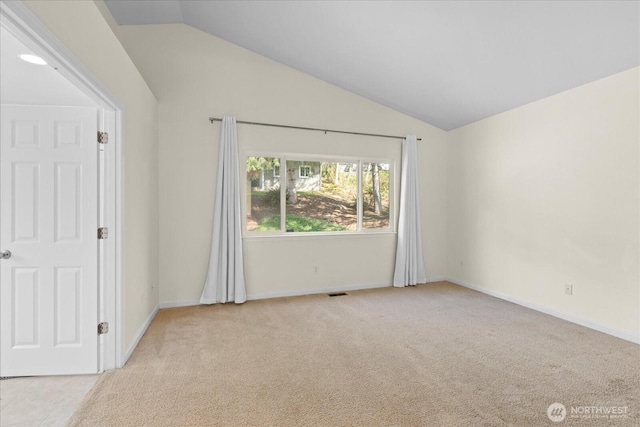 empty room with visible vents, light colored carpet, baseboards, and lofted ceiling