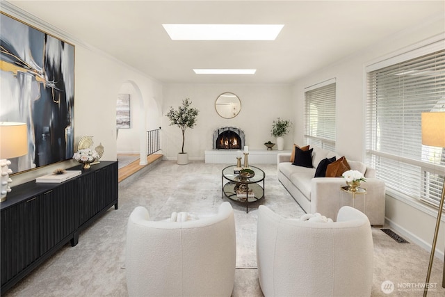 9115 SE 72nd Pl, Mercer Island, WA 98040 - living room featuring a lit fireplace, arched walkways, light colored carpet, visible vents, and a skylight