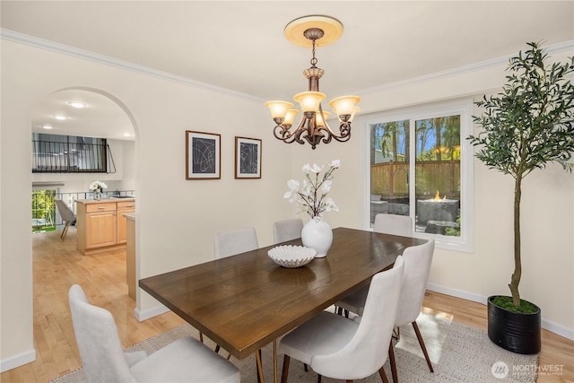 9115 SE 72nd Pl, Mercer Island, WA 98040 - dining area with crown molding, light wood-style floors, an inviting chandelier, arched walkways, and baseboards