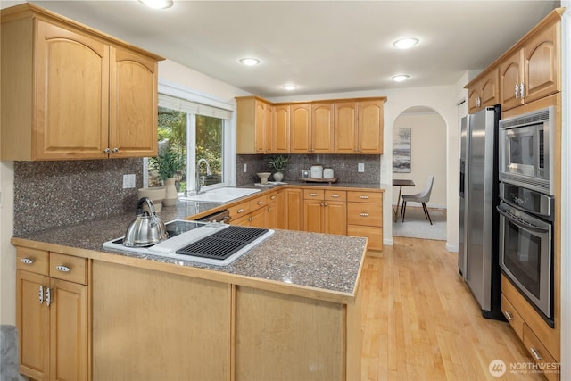 9115 SE 72nd Pl, Mercer Island, WA 98040 - kitchen with arched walkways, a sink, a peninsula, light wood finished floors, and stainless steel appliances