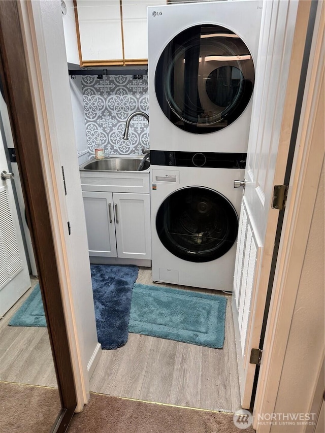69 N Pt, Bellingham, WA 98229 - clothes washing area with stacked washing maching and dryer, a sink, cabinet space, and wood finished floors