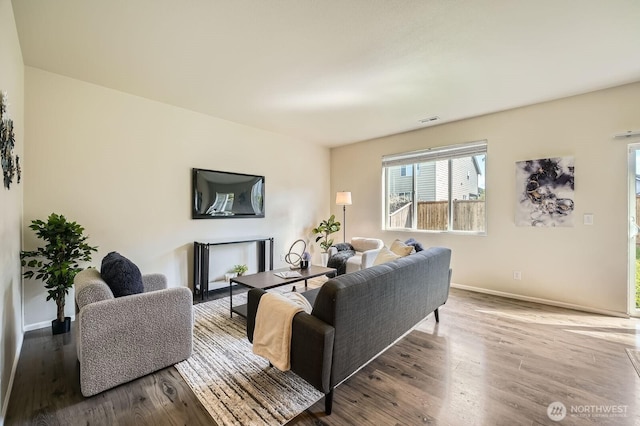 living area with visible vents, baseboards, and wood finished floors