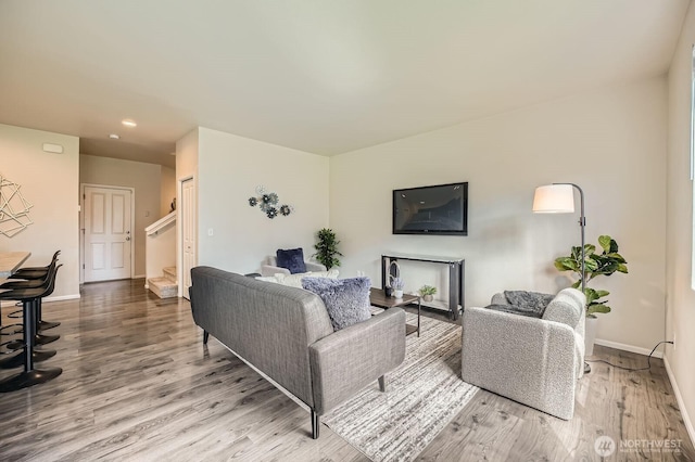 living area featuring stairs, recessed lighting, baseboards, and wood finished floors