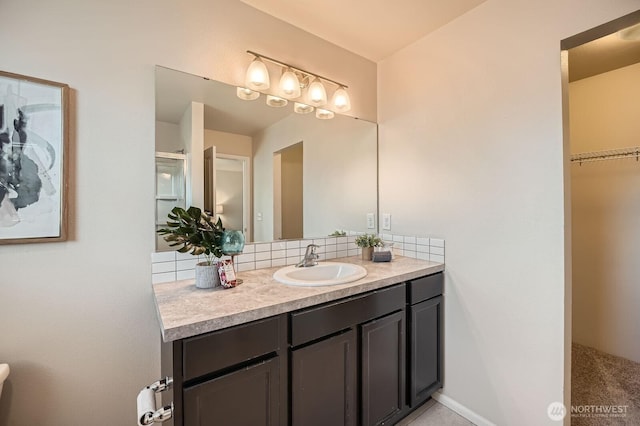 bathroom featuring vanity, a spacious closet, and tasteful backsplash
