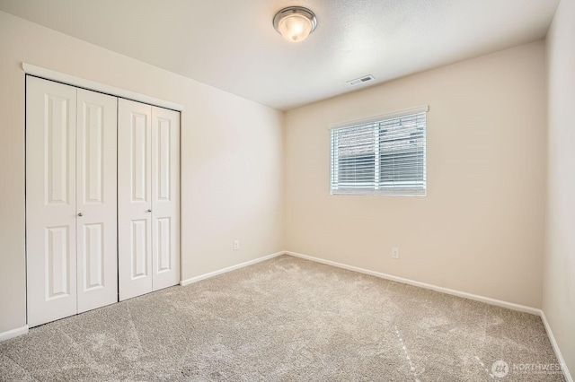 unfurnished bedroom featuring a closet, baseboards, carpet flooring, and visible vents