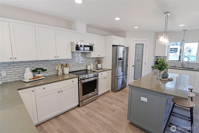 kitchen with decorative backsplash, white cabinetry, stainless steel appliances, and a sink