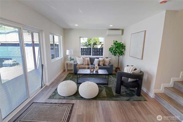 living area featuring baseboards, wood finished floors, recessed lighting, and a wall unit AC