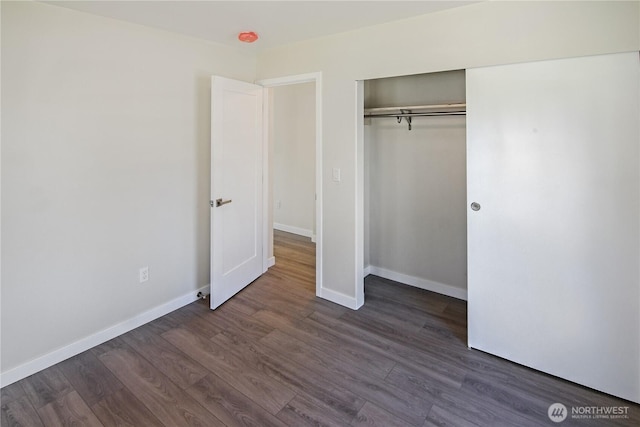 unfurnished bedroom with baseboards, a closet, and dark wood finished floors