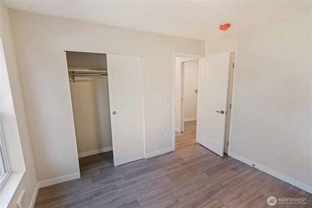 unfurnished bedroom with visible vents, baseboards, wood finished floors, and a closet
