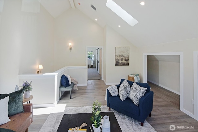 living area with a skylight, baseboards, wood finished floors, and high vaulted ceiling
