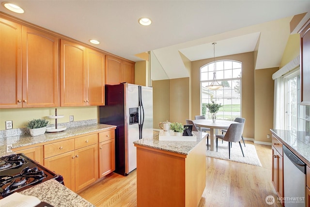 kitchen featuring pendant lighting, light wood-type flooring, light stone countertops, and stainless steel appliances