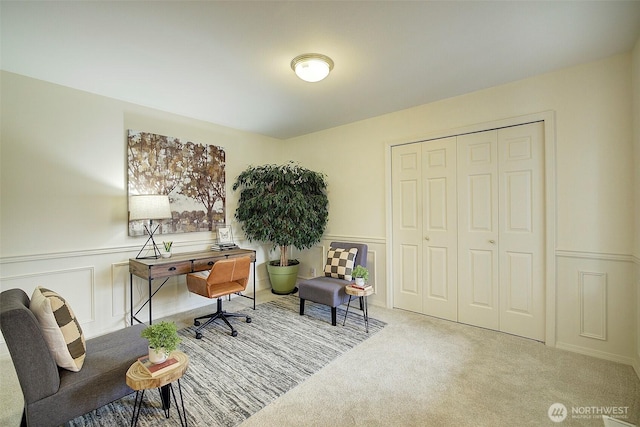 office area with a decorative wall, a wainscoted wall, and carpet flooring