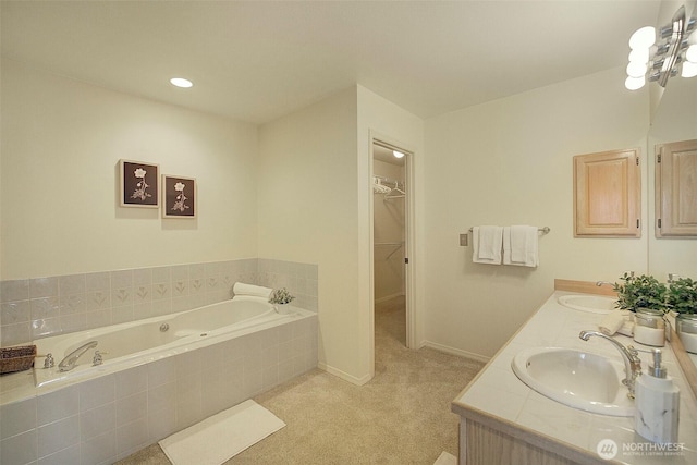 full bath with a sink, a spacious closet, double vanity, and a garden tub