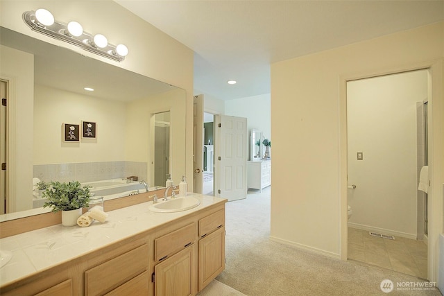bathroom with visible vents, a bath, baseboards, toilet, and vanity
