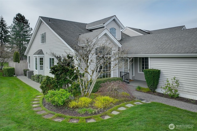 cape cod house featuring cooling unit, roof with shingles, and a front yard