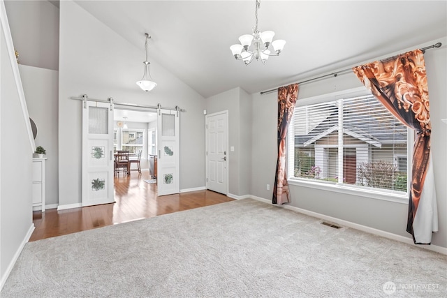 unfurnished dining area with visible vents, carpet floors, a barn door, lofted ceiling, and a notable chandelier