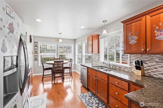 kitchen with a sink, light wood-style flooring, appliances with stainless steel finishes, and decorative backsplash