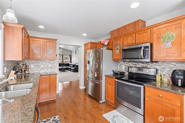 kitchen featuring decorative backsplash, light wood finished floors, a sink, and stainless steel appliances