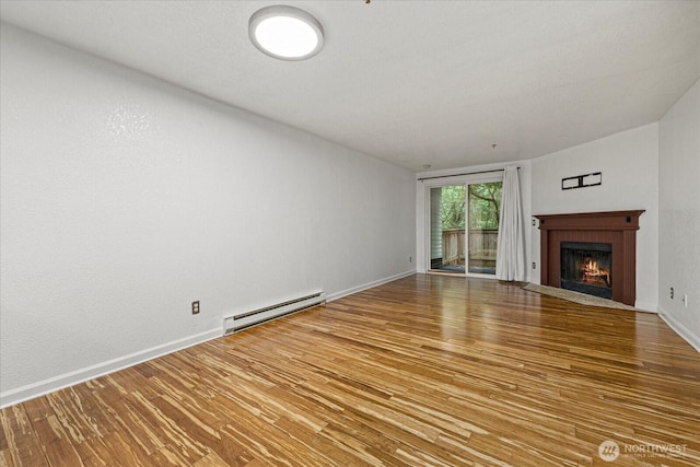 unfurnished living room with a baseboard radiator, wood finished floors, a fireplace with flush hearth, and baseboards