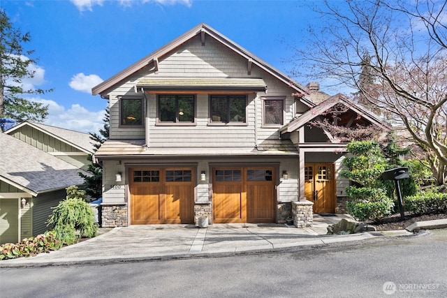 view of front of home with concrete driveway, stone siding, a chimney, and an attached garage