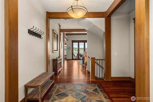 hall with baseboards, dark wood-style flooring, beam ceiling, and an upstairs landing