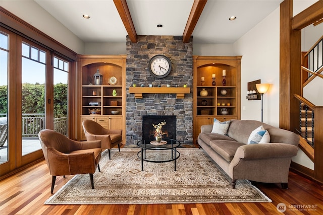 living area with beamed ceiling, a fireplace, recessed lighting, wood finished floors, and stairs