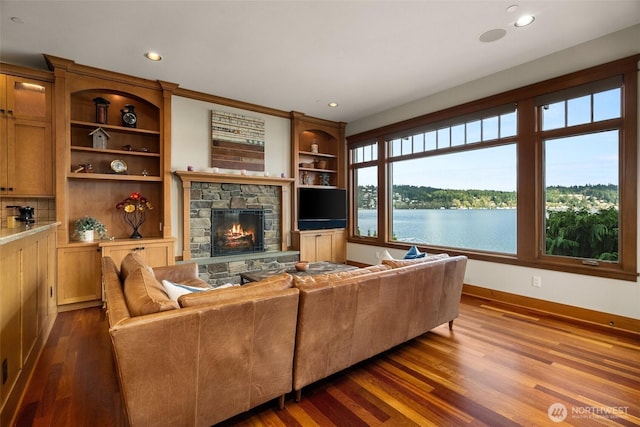 living area with recessed lighting, dark wood-style floors, a stone fireplace, and baseboards
