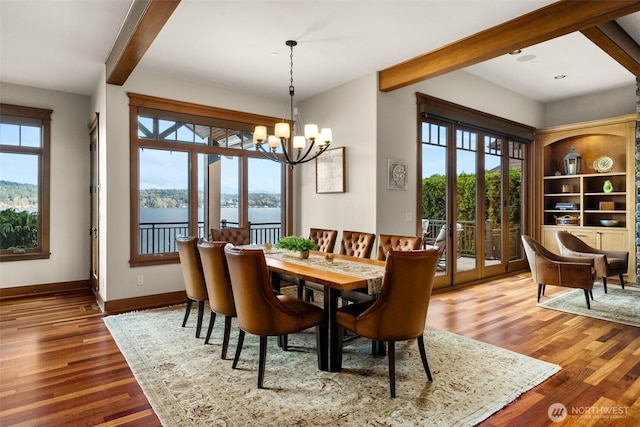 dining area featuring a wealth of natural light, a notable chandelier, and beam ceiling