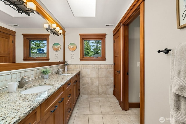 full bathroom featuring double vanity, tile patterned flooring, visible vents, tile walls, and a sink