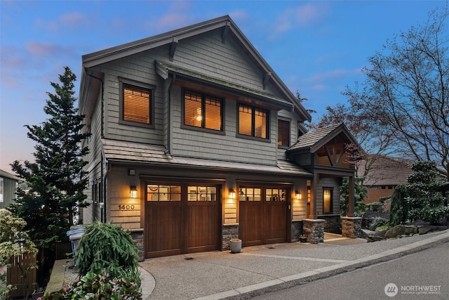 view of front of house featuring an attached garage, stone siding, and concrete driveway