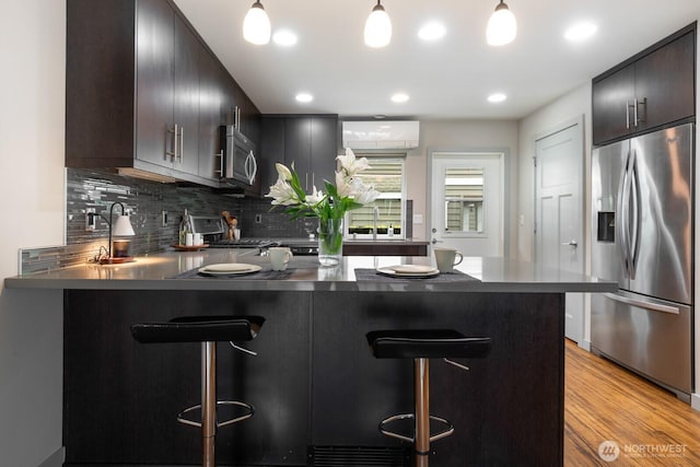 111 17th Ave Unit B, Seattle, WA 98112 - kitchen featuring dark countertops, a kitchen breakfast bar, stainless steel appliances, a peninsula, and backsplash