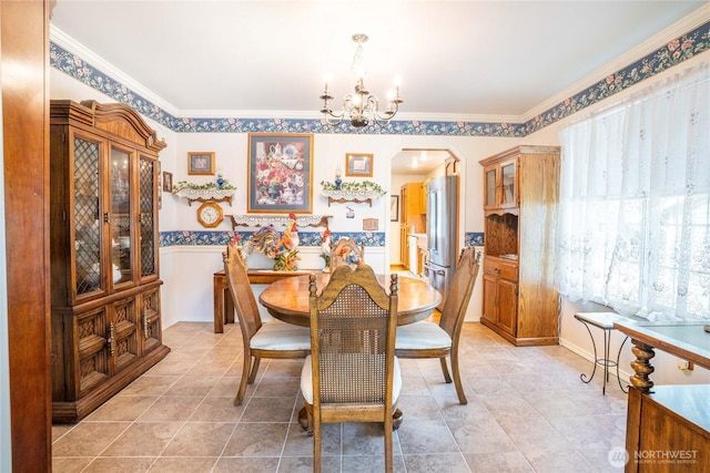 dining space with ornamental molding, arched walkways, an inviting chandelier, and light tile patterned floors