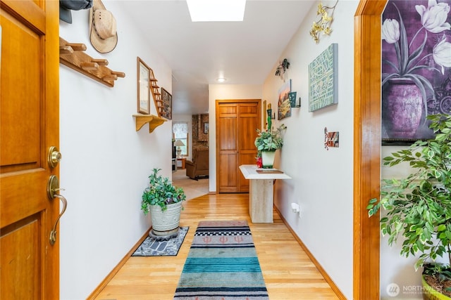 interior space with baseboards, wood finished floors, and a skylight