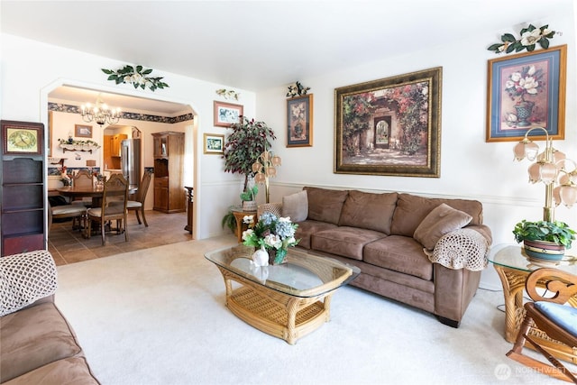 tiled living room featuring a chandelier, arched walkways, and carpet flooring