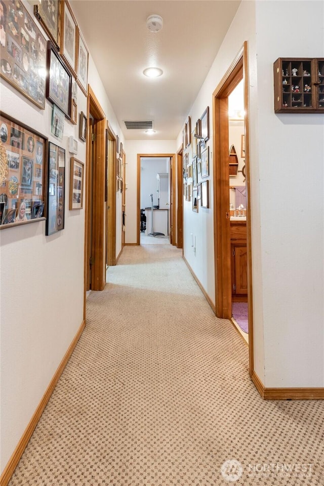 corridor with visible vents, baseboards, and carpet flooring