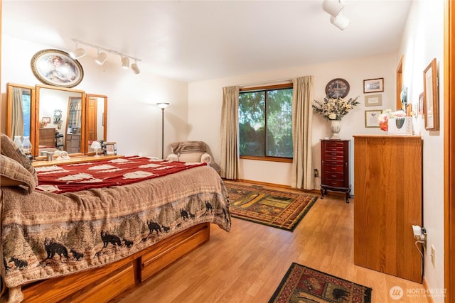 bedroom with rail lighting and wood finished floors