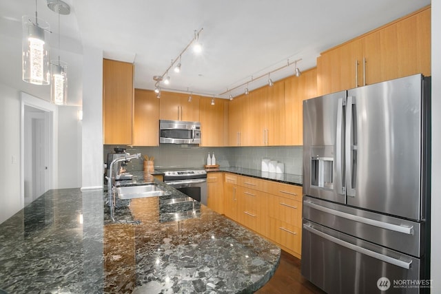 kitchen with pendant lighting, appliances with stainless steel finishes, tasteful backsplash, a sink, and dark stone countertops