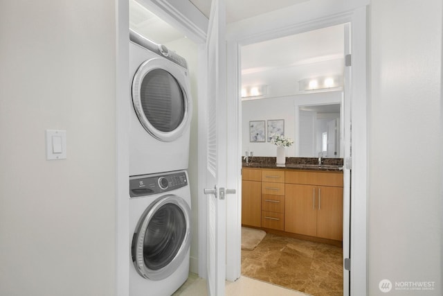 laundry area with laundry area, a sink, and stacked washer / dryer