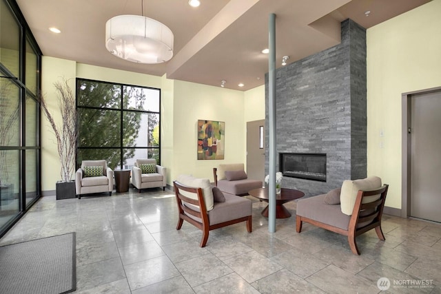 living room featuring recessed lighting, a high ceiling, and a fireplace