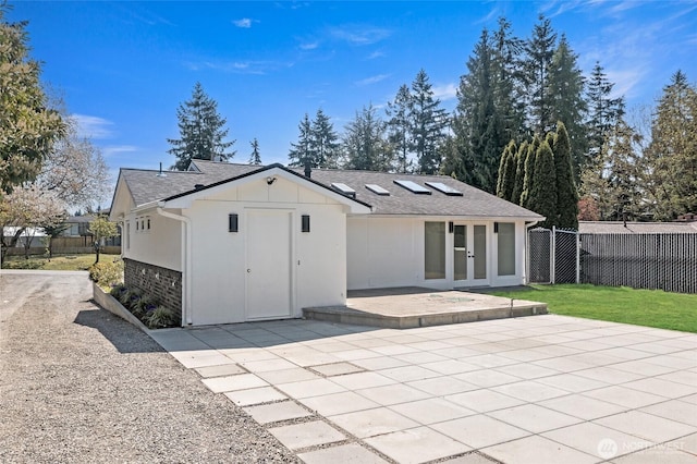 back of property with fence, a patio, roof with shingles, french doors, and board and batten siding