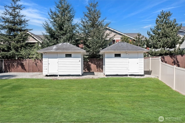 view of yard with an outdoor structure, a fenced backyard, and a shed