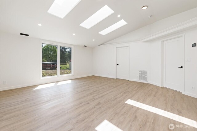 unfurnished room featuring visible vents, baseboards, lofted ceiling with skylight, recessed lighting, and light wood-type flooring