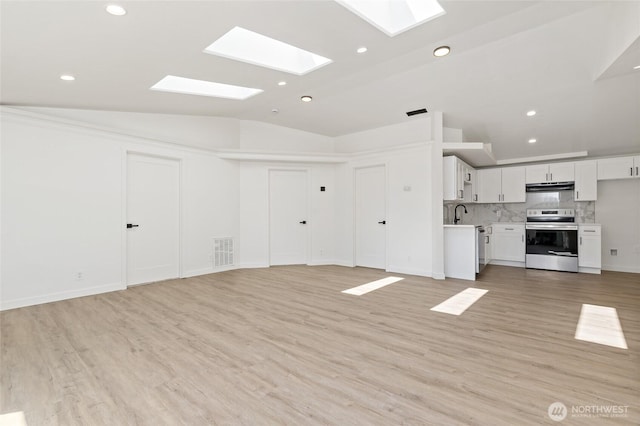 unfurnished living room with light wood-style floors, recessed lighting, lofted ceiling with skylight, and visible vents