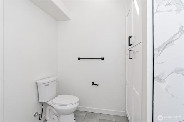 bathroom with toilet, baseboards, and marble finish floor